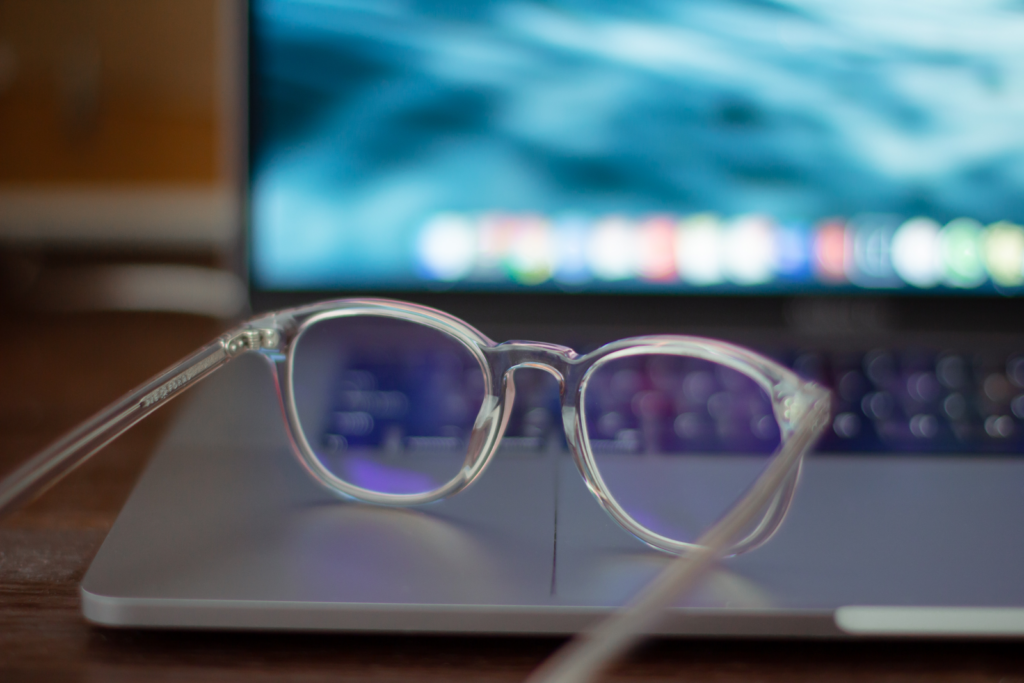 une paire de lunettes en plastique transparent avec un revêtement anti-lumière bleue assis sur un ordinateur portable ouvert